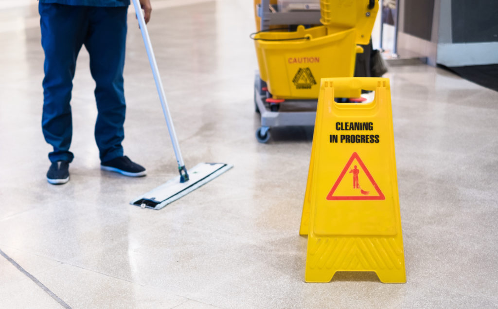 "janitor mopping tile floor" "caution wet floor sign" "janitor using mop bucket"